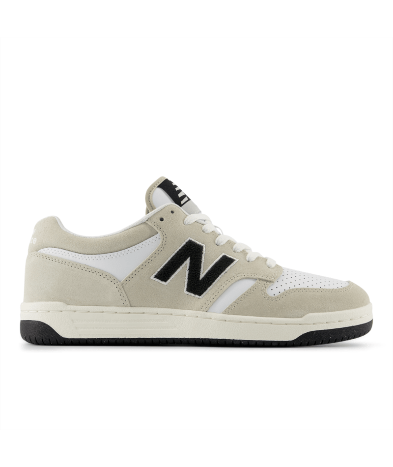 New Balance 480 sneakers in beige and white with black logo and perforated toe box, side view.