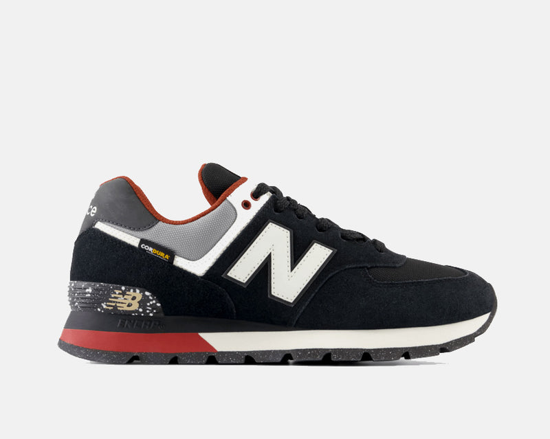 New Balance 574 Rugged sneakers in black suede with white logo, red accents, and Cordura fabric detailing, side view.