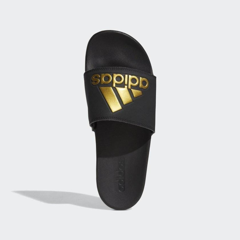 Adidas Adilette Comfort Slides in black with gold logo detailing and contoured footbed, top view.