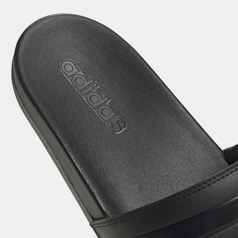 Adidas Adilette Comfort Slides in black with textured footbed and debossed Adidas logo, close-up view.