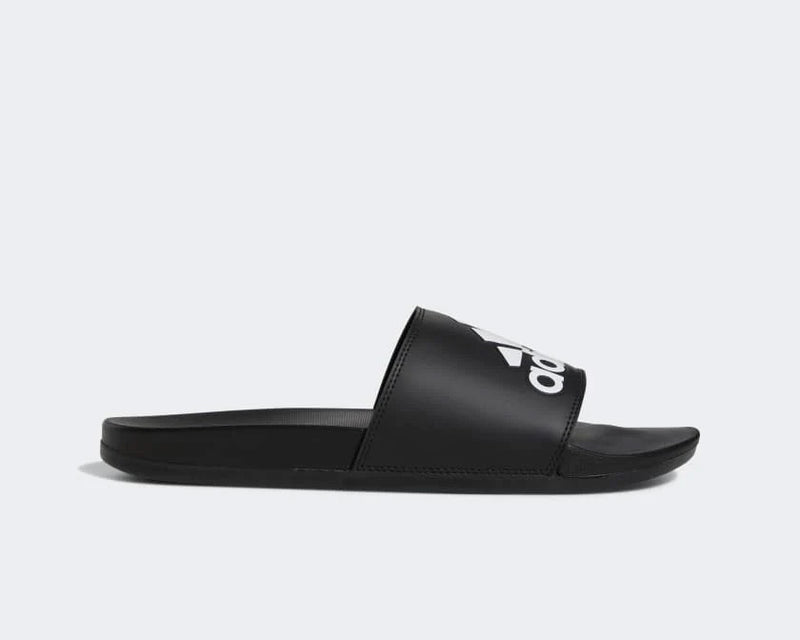 Adidas Adilette Comfort slides in black with white logo on synthetic strap and cushioned sole, side view.