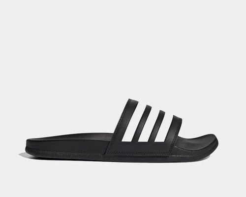 Adidas Adilette Comfort slide sandals in black with white stripes and cushioned footbed, side view.