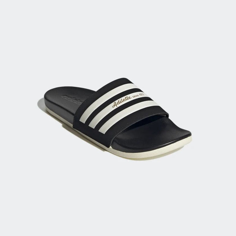 Adidas Adilette Comfort slides in black with white stripes and logo detail on the strap, angled front view showing cushioned footbed.