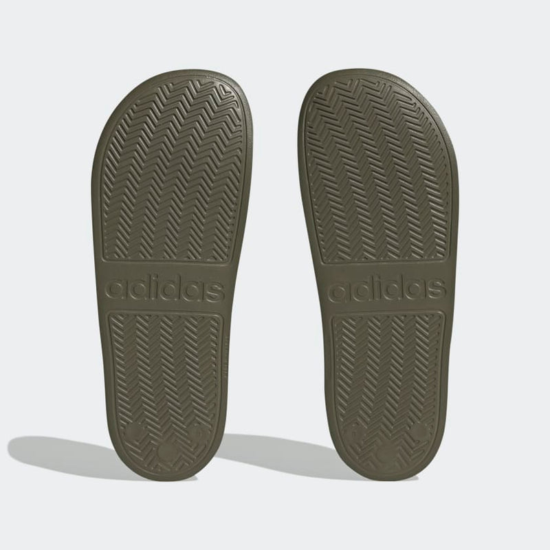 Adidas Adilette Comfort slides outsole in olive green with herringbone grip pattern and embossed Adidas logo, bottom view.