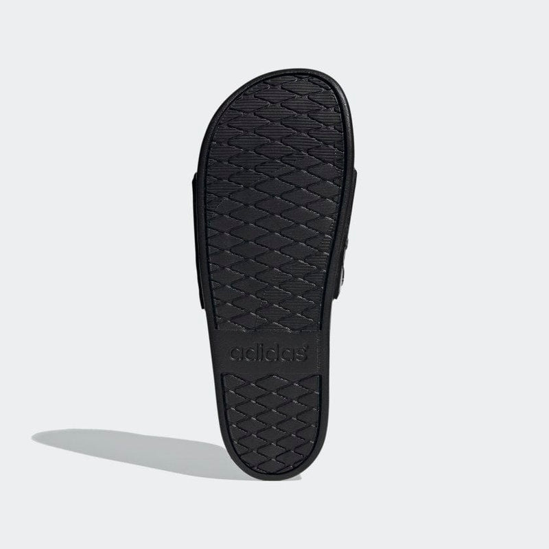 Adidas Adilette Comfort sandals showing textured black outsole with diamond pattern and embossed logo, sole view.