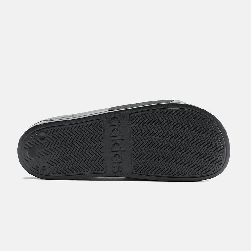 Adidas Adilette Shower Slides outsole in black rubber with textured grip pattern and embossed branding, bottom view