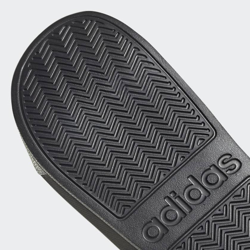 Adidas Adilette Shower Slides outsole view in black showing textured zig-zag grip pattern and embossed logo.