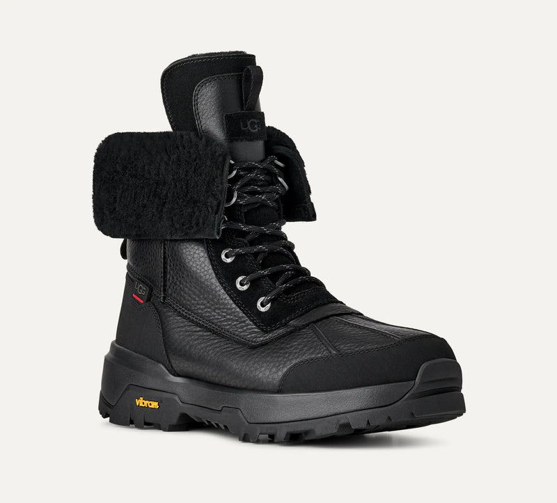 UGG Adirondack Boot XXV winter boot in black with textured leather upper, shearling lining, Vibram outsole, and lace-up design, front angle view.