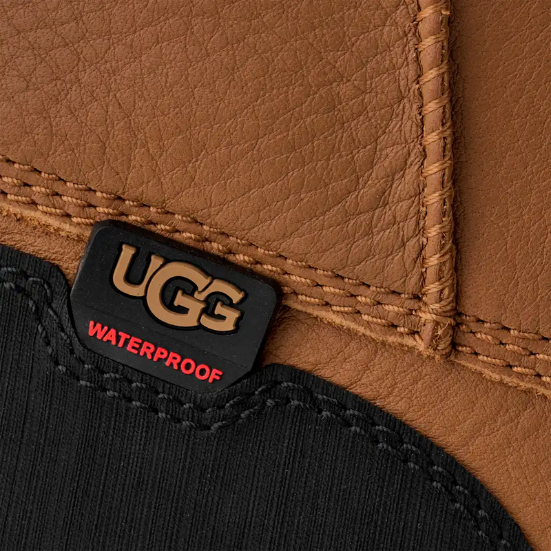 UGG Adirondack Boot XXV close-up showing waterproof tag and brown leather upper with reinforced stitching.
