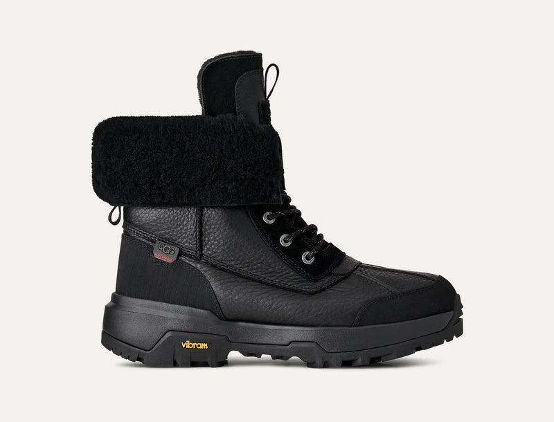 UGG Adirondack Boot XXV in black leather and suede with waterproof design, plush fur lining, and Vibram outsole, side view.