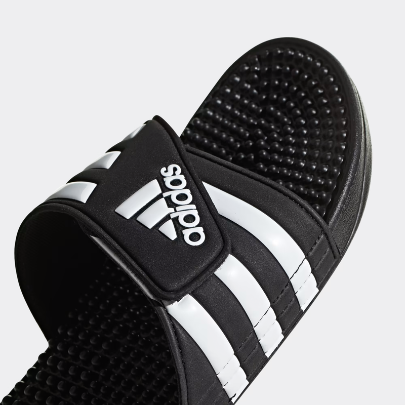 Adidas Adissage Slide sandals in black with white stripes, featuring adjustable strap and textured footbed, angled close-up view.