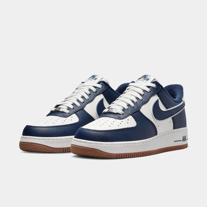 Nike Air Force 1 '07 LV8 sneakers in navy blue and white leather with perforated toe box and gum rubber outsole, angled front view.