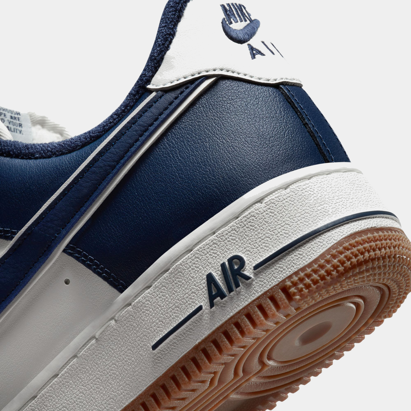 Nike Air Force 1 '07 LV8 sneakers with navy blue leather upper, white midsole, embossed "AIR" text, and gum outsole, side heel view.