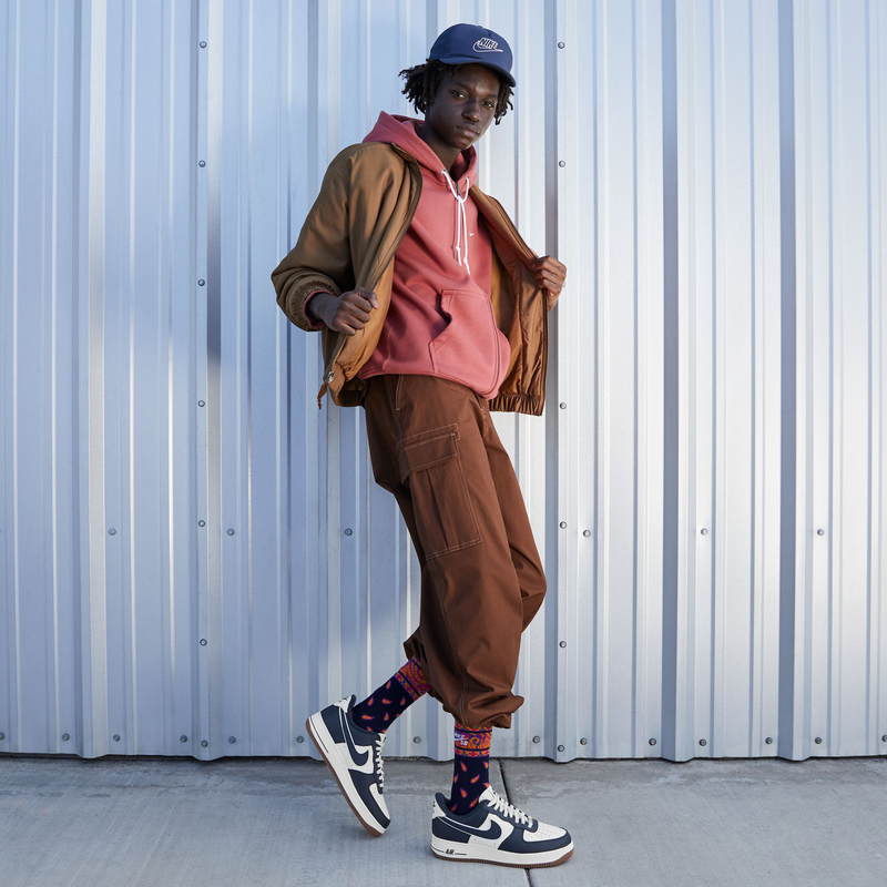 Nike Air Force 1 '07 LV8 shoes in navy and white with gum outsole, worn in an urban street-style setting.