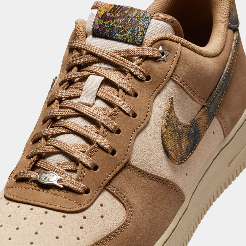 Nike Air Force 1 '07 RealTree sneakers in tan suede and off-white leather with multicolor camo Swoosh design, close-up view of upper and laces.