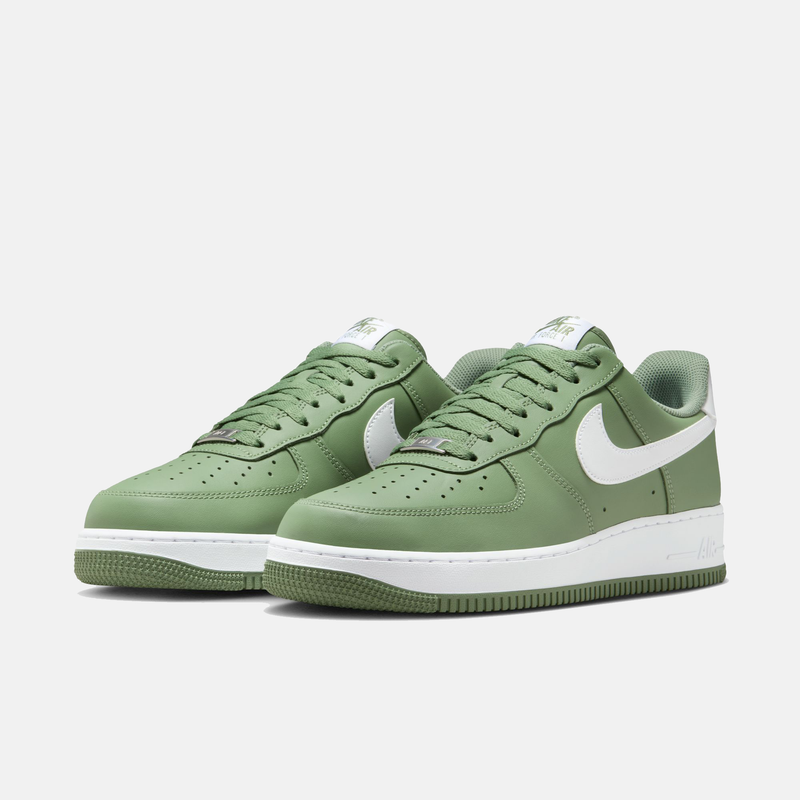 Nike Air Force 1 '07 sneakers in green with white accents, featuring a leather upper, perforated toe box, and classic rubber outsole, angled front view.