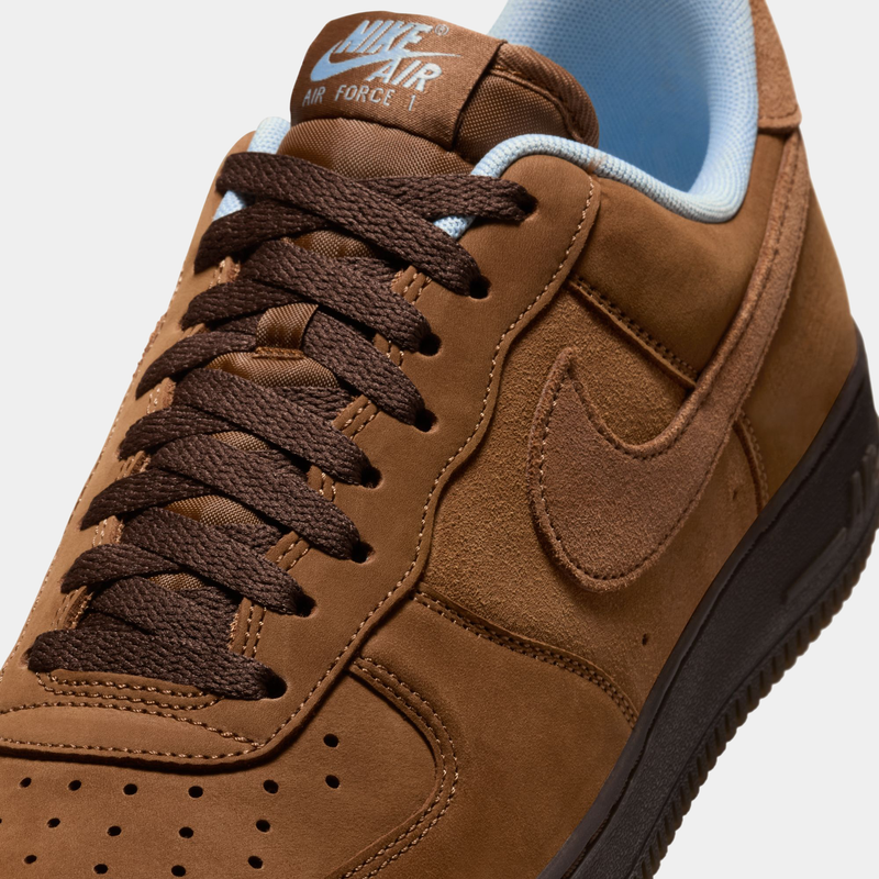 Nike Air Force 1 '07 sneakers in brown suede with tonal Swoosh logo, perforated toe box, and brown laces, close-up view.