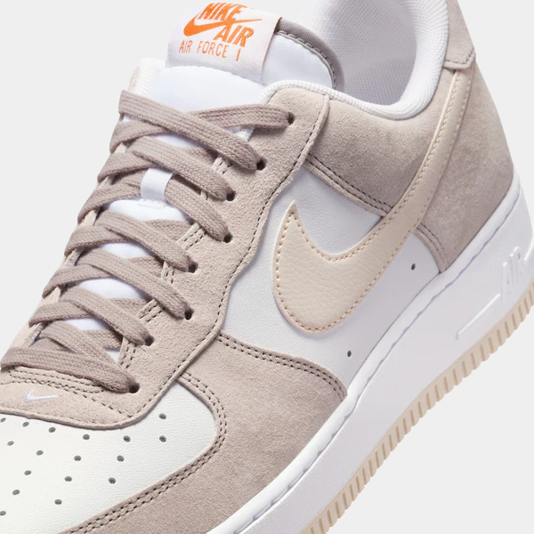 Nike Air Force 1 '07 sneakers in white and light taupe with a beige leather Swoosh, perforated toe box, and suede overlays, front angle.