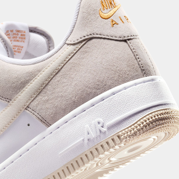 Nike Air Force 1 '07 sneakers in light gray suede with embossed "AIR" branding on white midsole, side angle close-up.