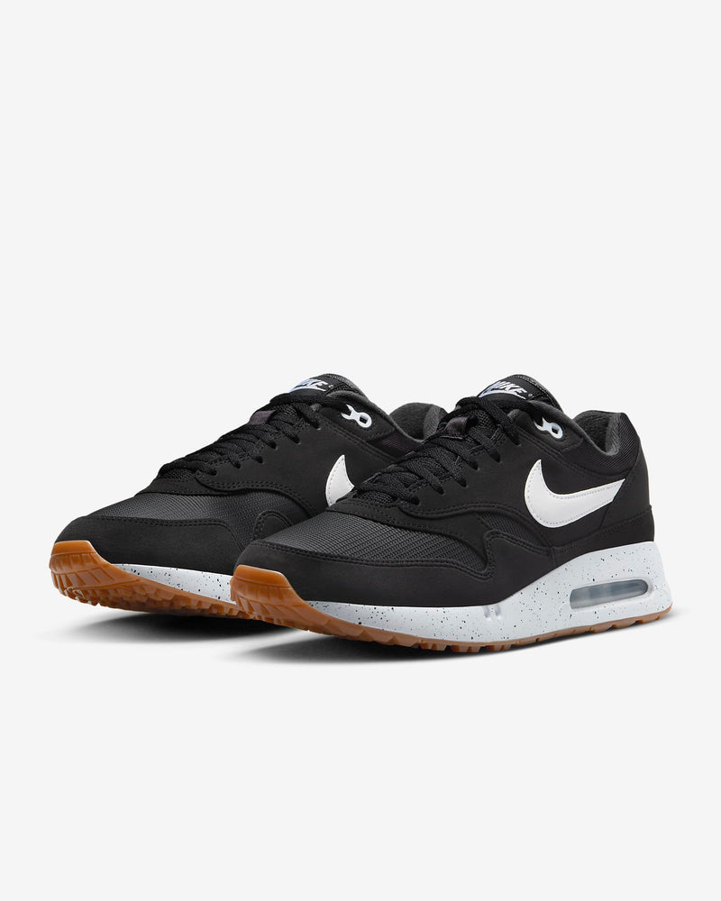 Nike Air Max 1 '86 OG Golf shoes in black with white Swoosh logo, speckled white midsole, and gum outsole, angled front view.