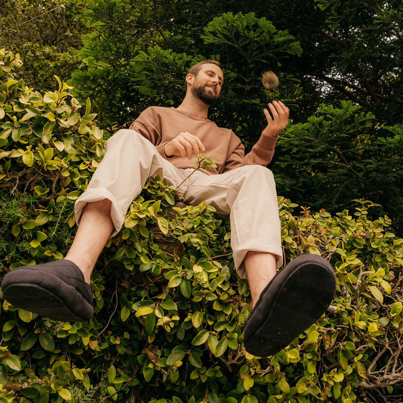 SeaVees Apres Puff Slip On shoes in black with quilted design and cushioned sole, lifestyle view outdoors on greenery.
