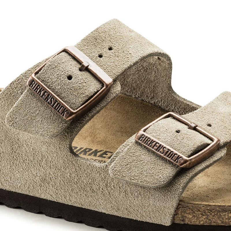 Birkenstock Arizona Suede sandals in taupe suede with adjustable bronze buckles and cork footbed, close-up side view.