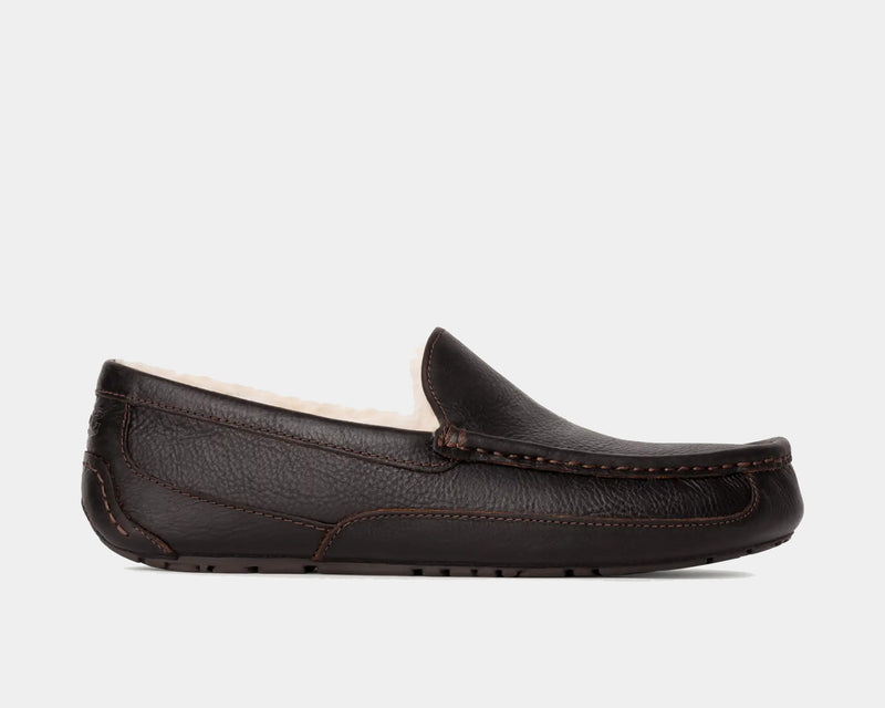 UGG Ascot Leather slippers in dark brown leather with moccasin stitching and plush shearling lining, side view.