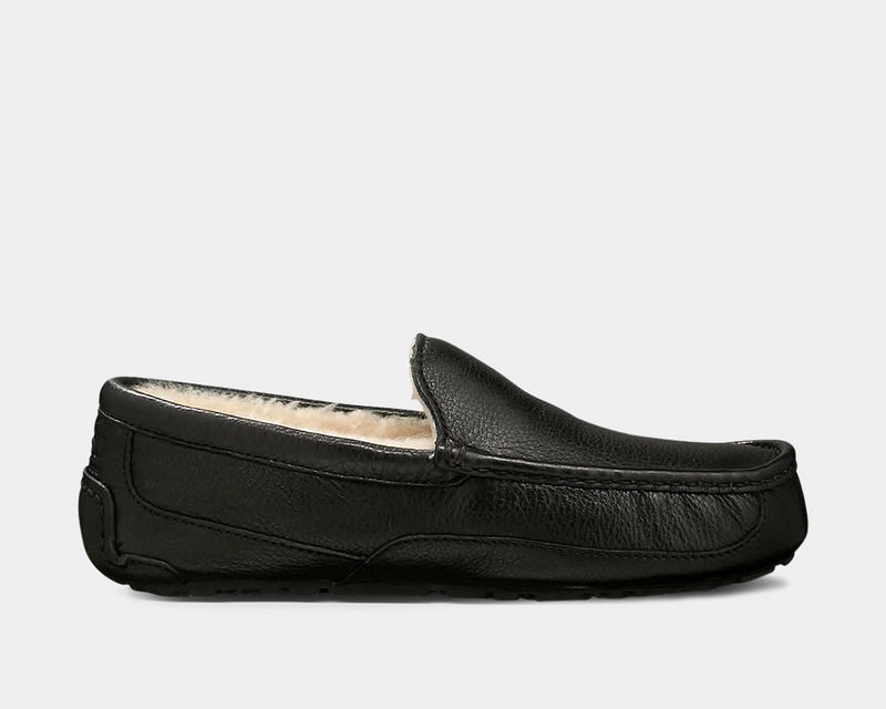 UGG Ascot Leather slippers in black full-grain leather with moccasin stitching and plush wool lining, side view.