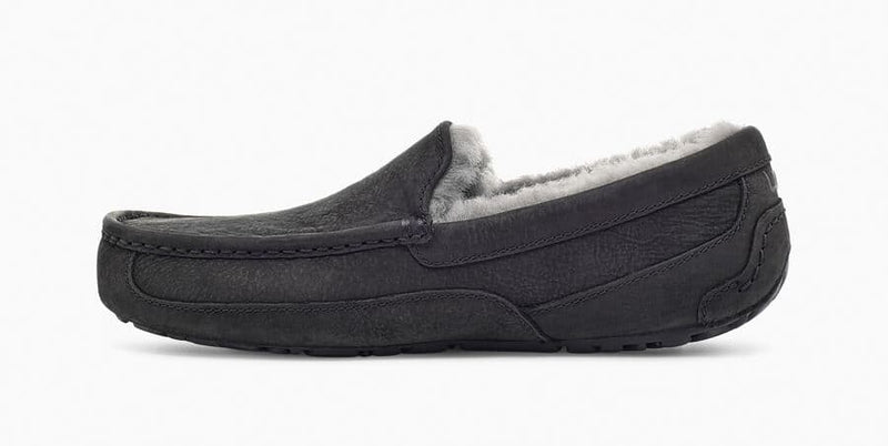 UGG Ascot Matte Leather slippers in black leather with plush wool lining and textured rubber outsole, side view.