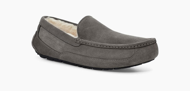 UGG Ascot Suede slippers in charcoal gray featuring a soft suede upper, plush shearling lining, and durable rubber outsole, side angle view.