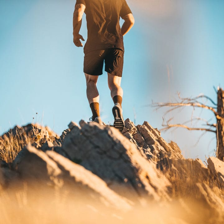 Darn Tough Boot Midweight Tactical Sock with Cushion in olive green worn by hiker on rocky terrain.