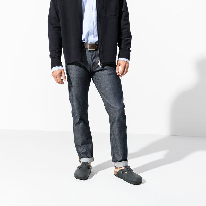 Birkenstock Boston Oiled Leather clogs in dark gray with adjustable strap and cork sole, worn by man standing.