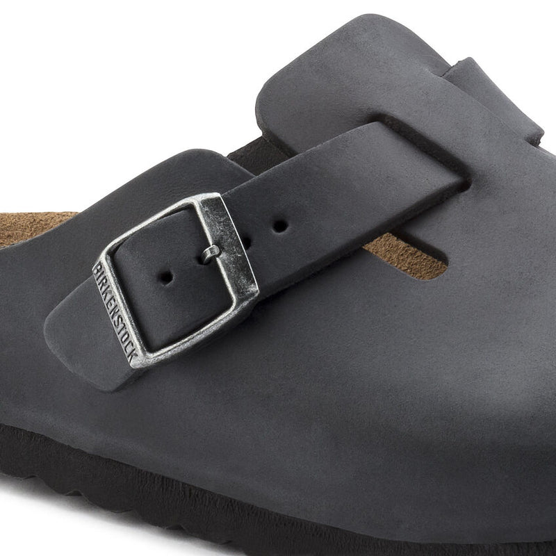Birkenstock Boston Oiled Leather clogs in black with adjustable buckle and smooth finish, close-up side view.