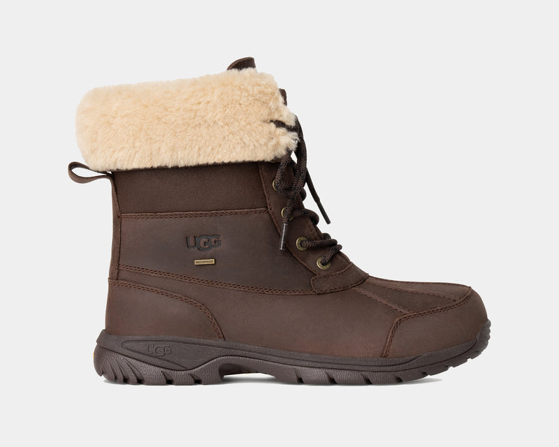 A brown, distressed leather winter boot with a fluffy white lining at the cuff, featuring a lace-up closure and a round toe.