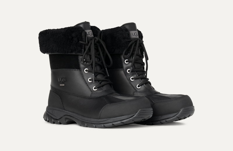 UGG Butte winter boots in black with leather upper, waterproof design, lace-up closure, and sheepskin collar, side angle.