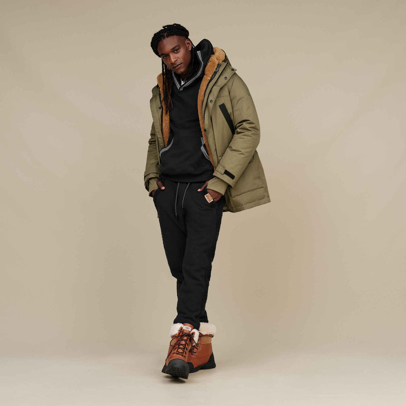 UGG Butte boots in chestnut brown with black outsole and sheepskin collar, worn in lifestyle setting.