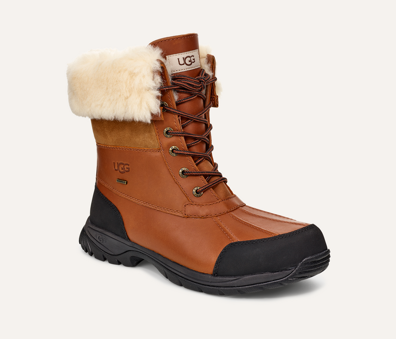 UGG Butte winter boots in brown leather with black rubber toe cap, shearling collar, and waterproof construction, side angle view.