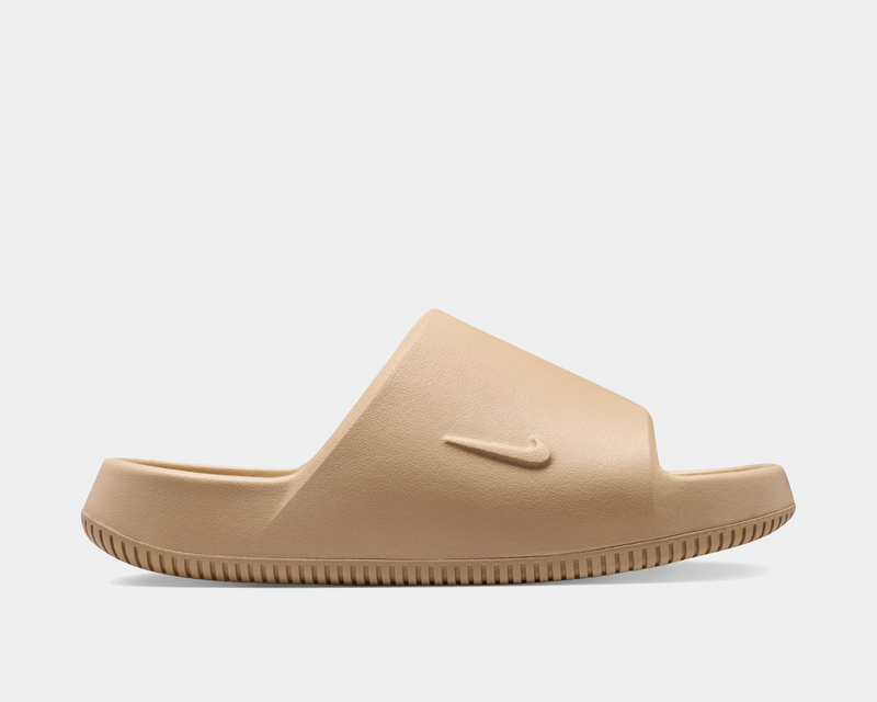 Nike Calm Slide 2.0 sandals in beige with textured footbed and embossed Nike logo, side view.