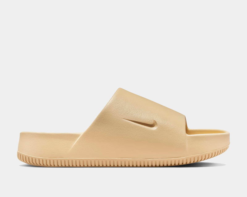 Nike Calm Slide sandals in beige with molded foam construction and embossed logo, side view.