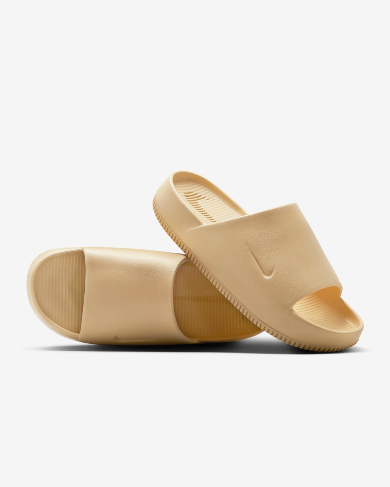 Nike Calm Slide sandals in beige with sleek minimalist design, textured footbed, and single-piece construction, angled side view.