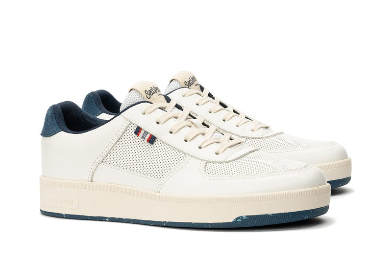 SeaVees Cardinal Sneaker in off-white with perforated leather upper, blue suede heel accent, and cream-colored sole, side angle view.