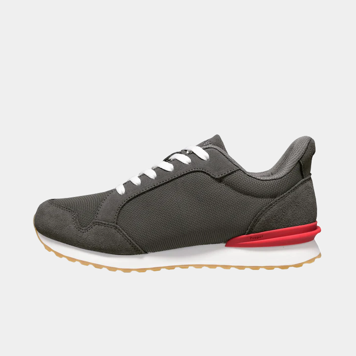 Propét Carmine Step In Sneakers in dark gray with a mesh and suede upper, white laces, red heel accent, and gum outsole, side view.