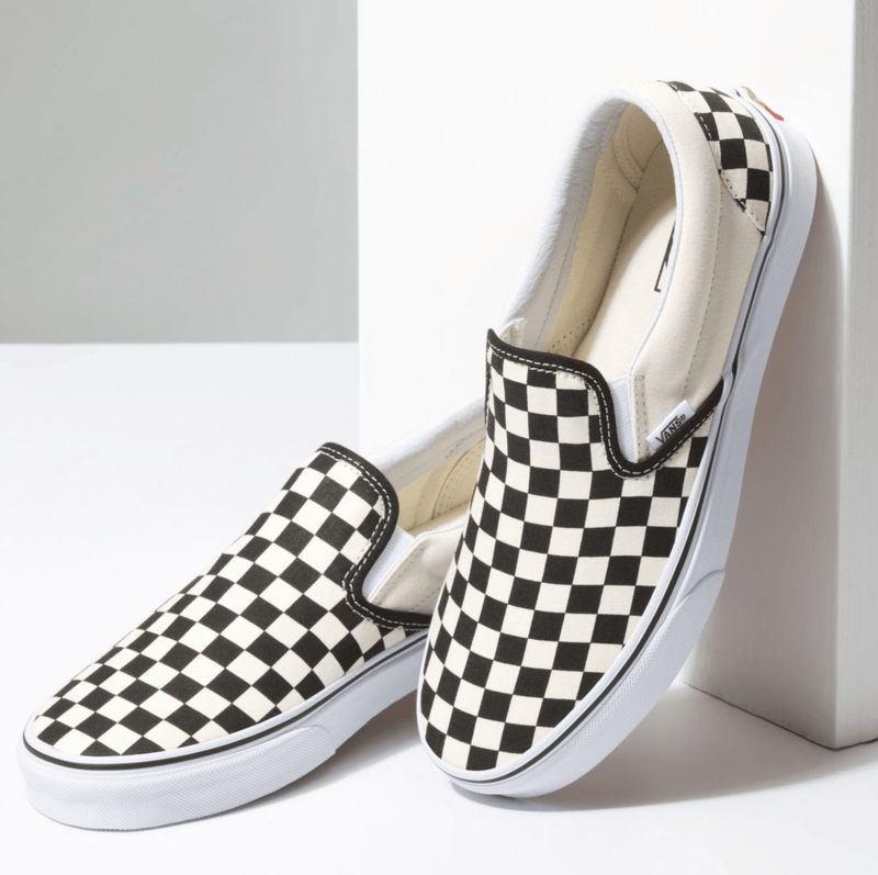 Vans Checkerboard Slip On shoes featuring black-and-white checkered canvas upper, white rubber sole, and elastic side accents, angled view.