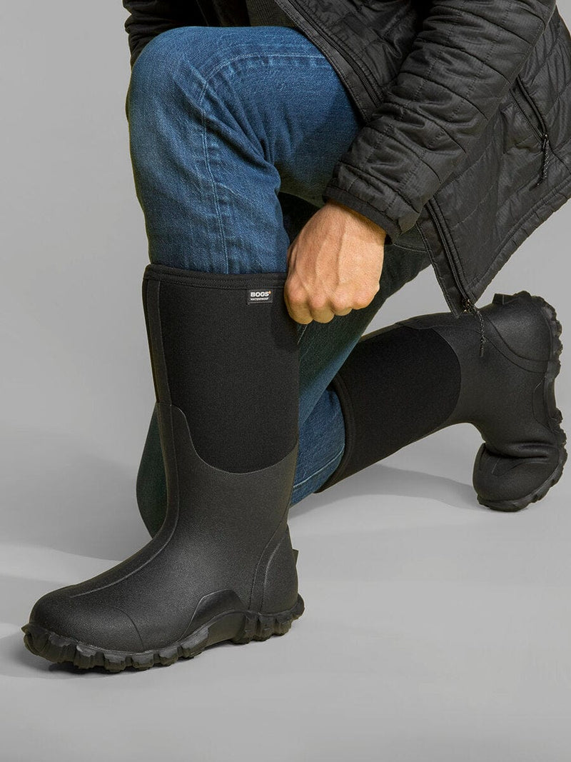 Bogs Classic High boots in black with waterproof construction and durable tread, worn by kneeling person.