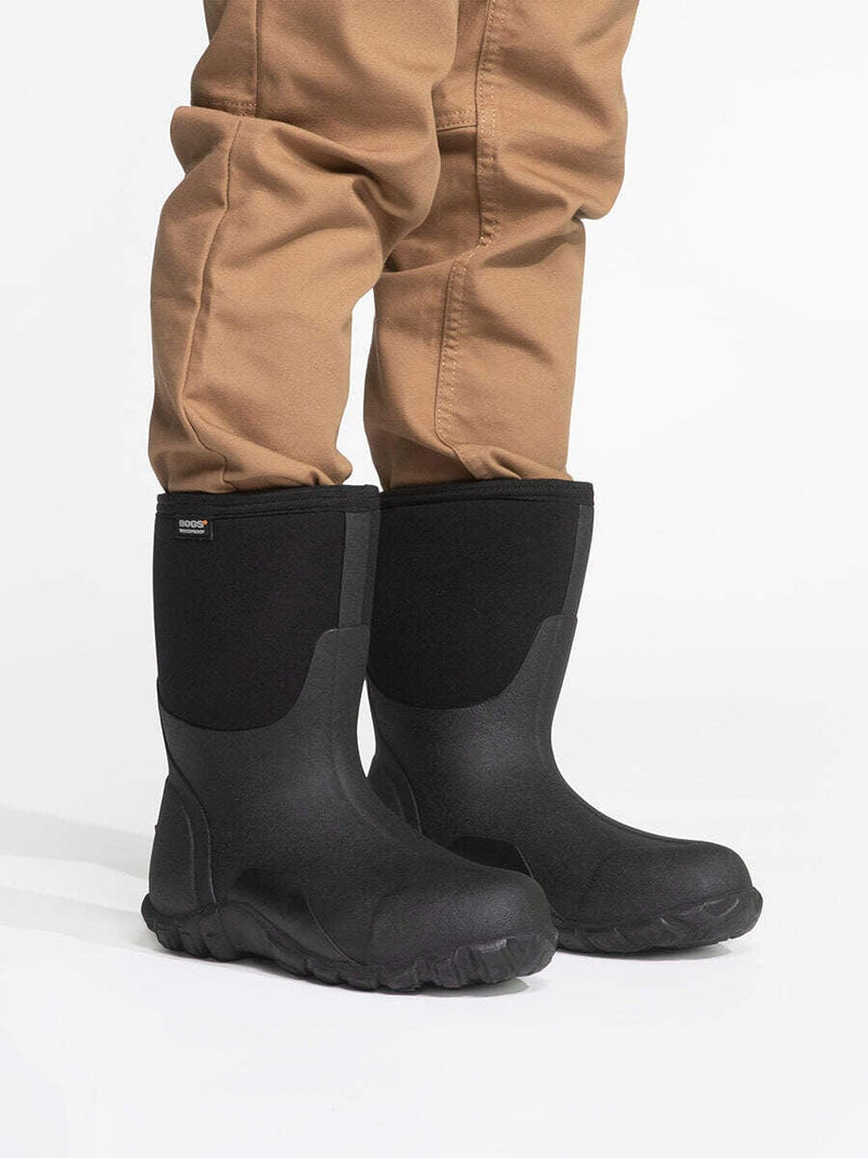 Bogs Classic Mid Boot black waterproof boots with durable rubber shell and neoprene upper, side view worn by person standing.