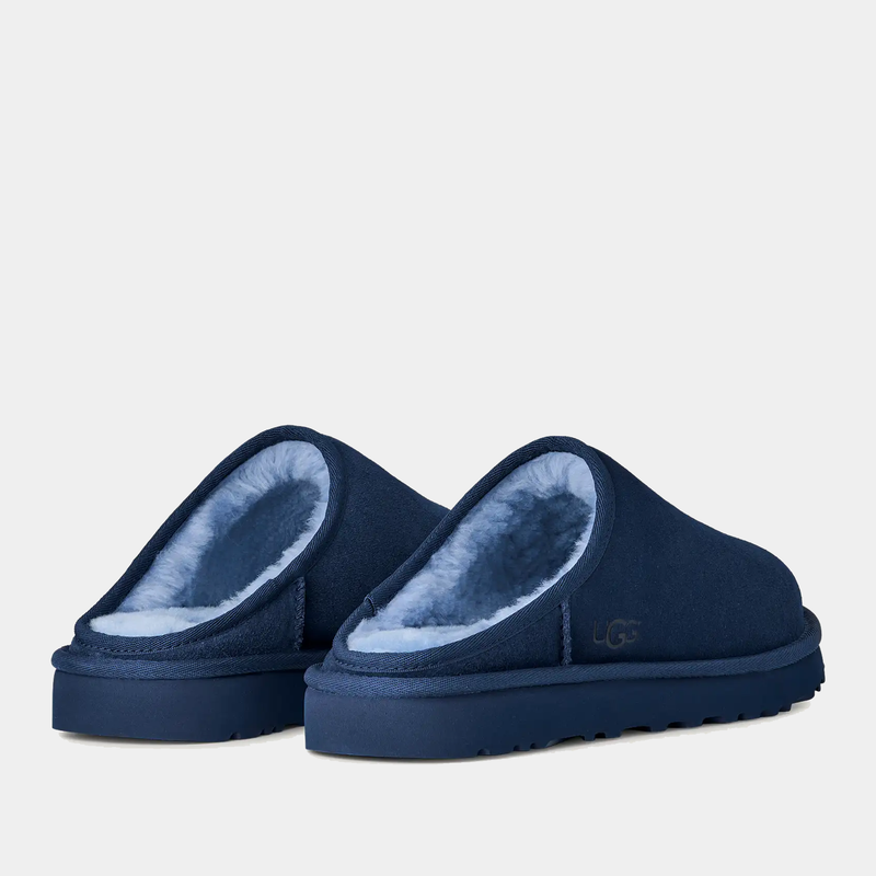 UGG Classic Slip-On slippers in deep navy blue with soft sheepskin lining and durable outsole, back angled view.