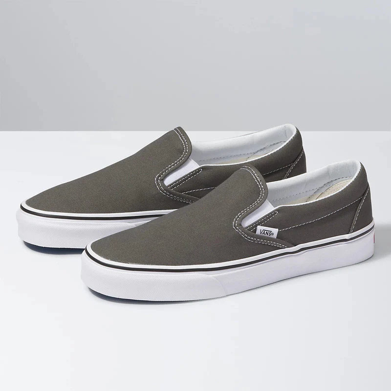 Vans Classic Slip On shoes in gray canvas with white stitching and rubber outsole, angled side view.