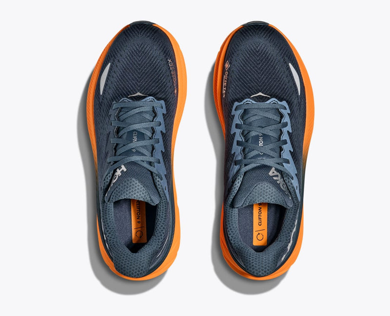 HOKA Clifton 9 GTX running shoes in navy blue with breathable mesh upper and vibrant orange midsole, top view.