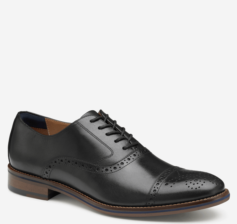 Johnston & Murphy Conard Cap Toe dress shoes in black leather with brogue perforations, lace-up closure, and stacked wooden sole, side view.