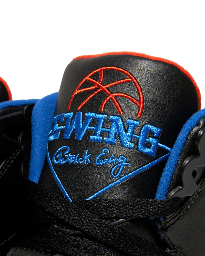Ewing Athletics CONCEPT OG PE sneakers featuring black leather upper, blue embroidered branding, and orange accents, close-up of tongue logo.